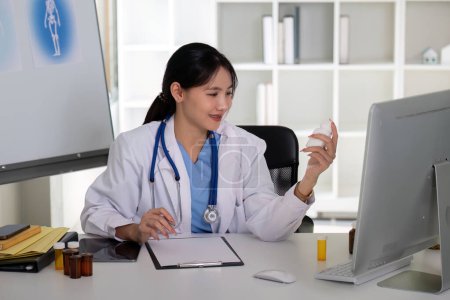 Asian Female Doctor Analyzing Medication Bottle in Clinic.