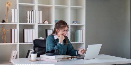 Photo for Young woman working on a laptop at a home office desk. - Royalty Free Image