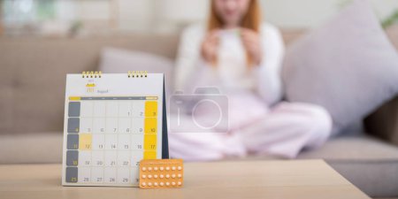 Foto de Pastillas anticonceptivas con calendario en la mesa en casa. Concepto de anticoncepción, planificación familiar y atención médica para mujeres. - Imagen libre de derechos