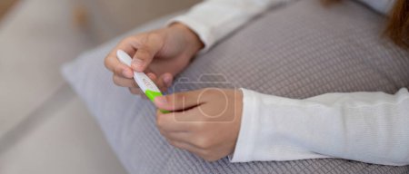 Foto de Woman examining pregnancy test results with concern. Concept of personal health, anxiety, and reproductive issues. - Imagen libre de derechos