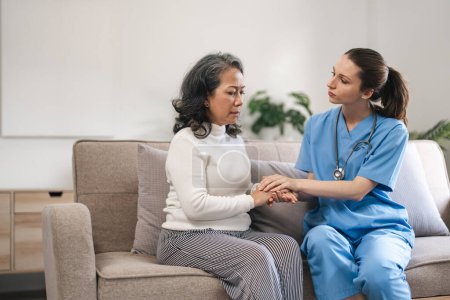 Photo for Nurse or caregiver comforting senior woman patient on sofa in home. Healthcare and emotional support concept. - Royalty Free Image
