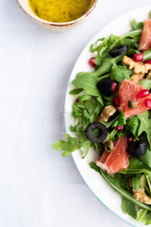 Photo for Rocket (arugula) and lamb's lettuce salad with grapefruit, pomegranate seeds, black olives, capers, walnuts, and mustard vinaigrette dressing - Royalty Free Image