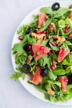 Photo for Rocket (arugula) and lamb's lettuce salad with grapefruit, pomegranate seeds, black olives, capers, walnuts, and mustard vinaigrette dressing - Royalty Free Image