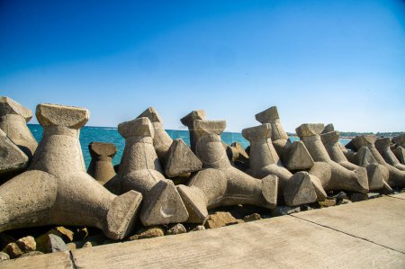 Foto de Estos bloques se colocan estratégicamente a lo largo de la playa o costa para crear una barrera que absorbe el impacto de las olas durante las tormentas o mareas altas.. - Imagen libre de derechos