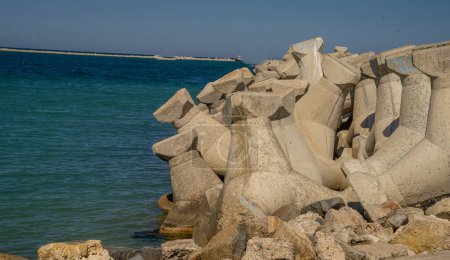 Téléchargez les photos : Ces blocs sont placés stratégiquement le long de la plage ou du rivage pour créer une barrière qui absorbe l'impact des vagues pendant les tempêtes ou les marées hautes.. - en image libre de droit