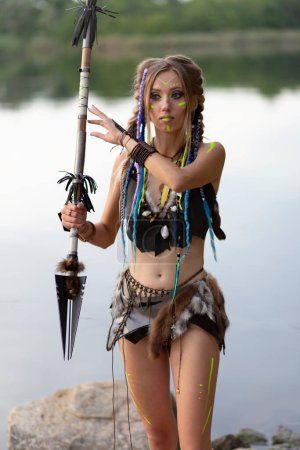Téléchargez les photos : Amazone femme dans un costume médiéval de fourrure avec une lance à la main, dans la peinture de guerre. - en image libre de droit