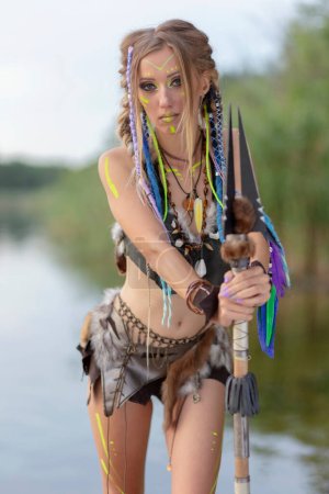 Téléchargez les photos : Amazone femme dans un costume médiéval de fourrure avec une lance à la main, dans la peinture de guerre. - en image libre de droit