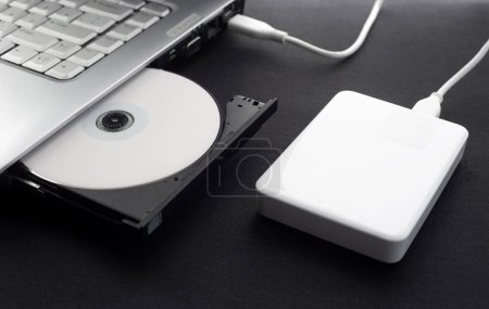 Photo for External hard drive connected to a laptop, open optical drive of a laptop with a disk, protected data, Data storage concept, on a dark background - Royalty Free Image