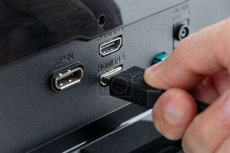 Téléchargez les photos : Connecteur HDMI connecté au moniteur, insérer à la main un câble HDMI - en image libre de droit
