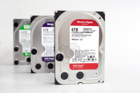 Photo for Dnipro, Ukraine - March 16, 2024: 3 x 6TB Hard Drives, 35" Six Terabyte Hard Drives, Western Digital Red, Purple, Green, for Server & CCTV Systems, Selective Focus on isolated white background. - Royalty Free Image