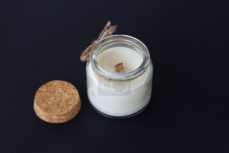 aromatic candle with a wooden wick in a glass candlestick, close-up on a dark background