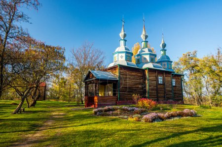 Téléchargez les photos : Église historique de la Trinité en bois de Pereiaslav, Ukraine. L'église est dans un style orthodoxe ukrainien traditionnel avec des dômes bleus et des croix d'or sur le dessus. Journée ensoleillée d'automne - en image libre de droit