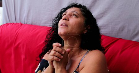 Hopeful Brazilian woman looking up seeking divine help. Latin person praying to God