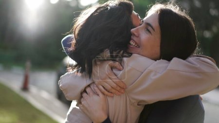 Foto de Two happy female best friends hugging each other. Women embrace reunion outdoors at park - Imagen libre de derechos