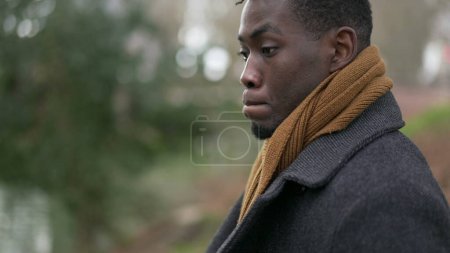 Téléchargez les photos : Thoughtful contemplative young black man standing outside in reflection and thoughts - en image libre de droit