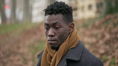 Téléchargez les photos : Thoughtful contemplative young black man standing outside in reflection and thoughts - en image libre de droit