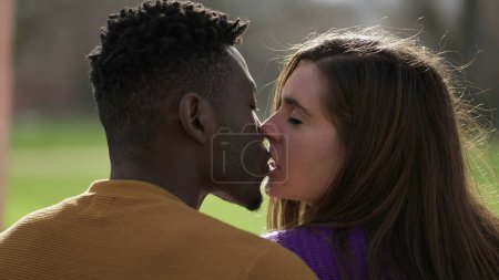 Young interracial kissing, back of two people kiss