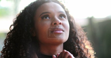 Femme africaine priant Dieu à l'extérieur cherchant la foi et ESPOIR dehors dans la lumière du soleil