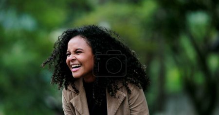 Photo for Young beautiful black African woman laughing and smiling outside at park, real life laugh - Royalty Free Image