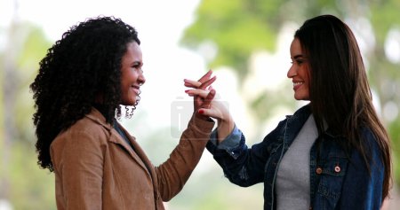 Two diverse young women joining hands in unity, black and white girls uniting hand together, diversity concept