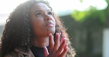 Foto de Mujer negra preocupada pidiendo ayuda a Dios orando - Imagen libre de derechos