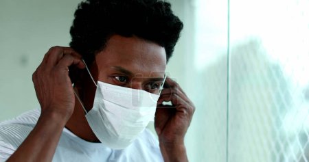 Téléchargez les photos : Black man putting on preventive mask during pandemic - en image libre de droit