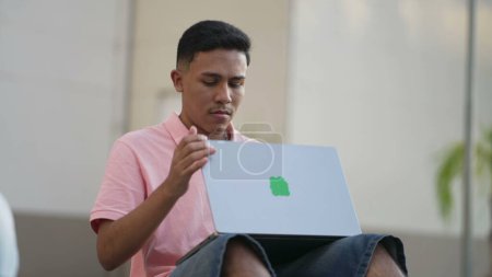 Téléchargez les photos : Un jeune hispanique éteint son ordinateur portable. Homme tournant ordinateur mettant dispositif moderne loin. Guy écran de fermeture - en image libre de droit