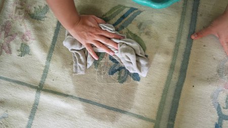 Foto de Limpieza alfombra eliminación mancha primer plano mano frotamiento alfombra con tela - Imagen libre de derechos