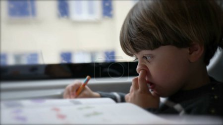 Cueillette concentrée du nez de l'enfant pendant ses devoirs assis à l'intérieur d'un train en mouvement