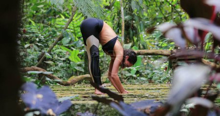 Téléchargez les photos : Yogi femme étirant les jambes à l'extérieur dans la jungle tropicale - en image libre de droit