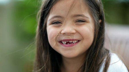 Photo for Portrait of a happy little girl closeup face with missing teeth. Joyful female child toothless front tooth smiling - Royalty Free Image
