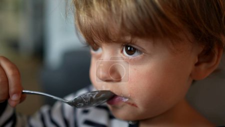 Téléchargez les photos : Toddler 2 year old baby eating yogurt - en image libre de droit