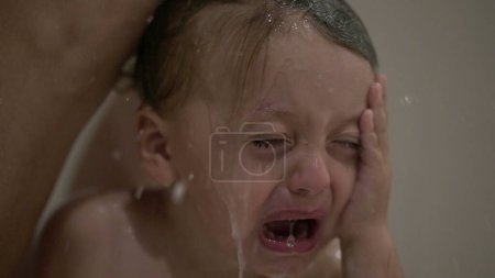 Photo for Crying baby washing hair in shower, shampoo itchy eyes in bath. Upset child cries - Royalty Free Image