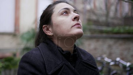 Photo for Tired woman in 30s standing outside in the cold wearing a winter coat waiting - Royalty Free Image