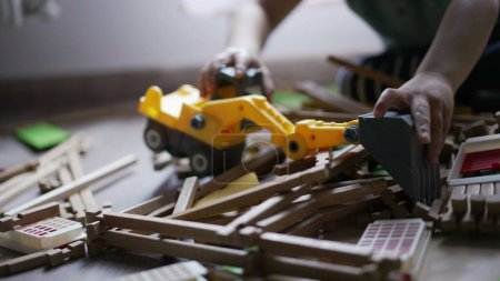 Téléchargez les photos : Enfant détruisant jouet maison en bois avec petit tracteur bulldozer. Un petit garçon destructeur jouant à la maison dans la salle de jeux - en image libre de droit