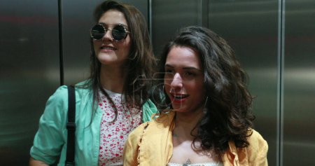 Téléchargez les photos : Young women in front of elevator mirror preparing to go out - en image libre de droit