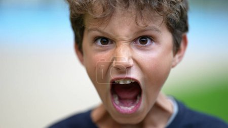 Photo for One angry young boy screaming to camera. Preteen child open mouth yelling in anger. Furious enraged male kid screaming - Royalty Free Image
