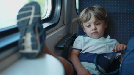 Photo for One upset child with feet on table while traveling by train. Mischievous small kid not behaving on moving transportation - Royalty Free Image