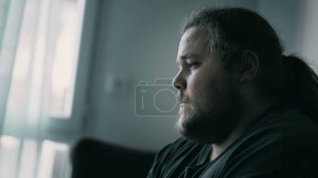 Depressed man sitting on couch. Sad unhappy person suffering from mental illness