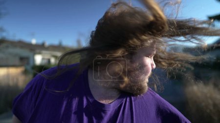 Photo for Funny Young happy man takes off the rubber band from his hair outside. An overweight person feeling free shaking head with long hair - Royalty Free Image