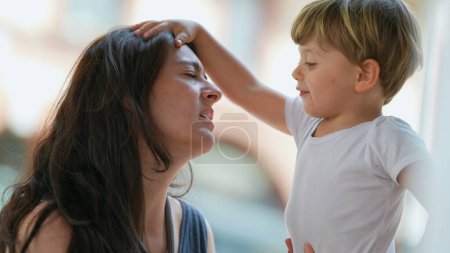 Photo for Parenting stress. Patient mother. Little boy hitting parent in the head with hand. Child misbehavior outside. Lifestyle real life stressful moment - Royalty Free Image