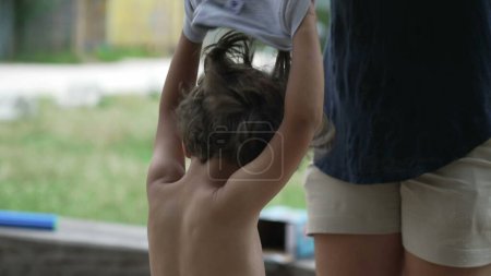 Photo for Mother removing child shirt from small boy son outside. Parent takes off kid clothes outdoors - Royalty Free Image