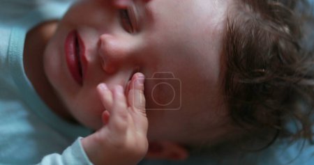 Photo for Tired baby rubbing eye and face with hands, sleepy child infant - Royalty Free Image