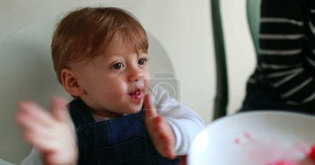 Foto de Niño pequeño aplaudiendo de la mano mientras come postre de sandía - Imagen libre de derechos