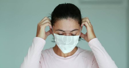 Téléchargez les photos : Woman putting face mask to protect from virus - en image libre de droit