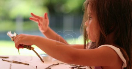Téléchargez les photos : Petite fille jouant artisanat avec bâton à la maison - en image libre de droit