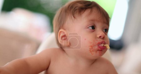 Téléchargez les photos : Cute baby eating and chewing with mouth full. Adorable infant toddler chews food - en image libre de droit
