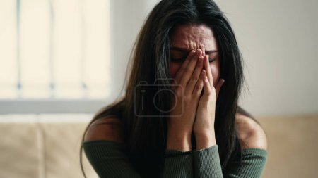 Foto de Mujer joven angustiada abrumada por la ansiedad y la tristeza, sintiéndose indefensa y perdida en casa - Imagen libre de derechos