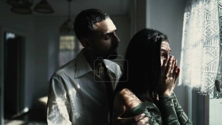 Un petit ami arabe bienveillant réconfortant sa petite amie larmoyante par la fenêtre pendant un moment difficile, montrant du soutien et de l'empathie