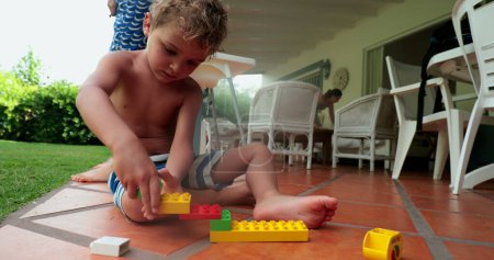 Photo for Child boy playing with building blocks together at home, candid kid plays with by himself with construction pieces - Royalty Free Image